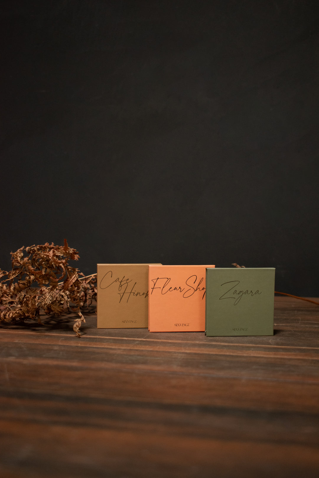 Sixvignt Solid Perfume cases are lined up on a wooden table in front of a dark background